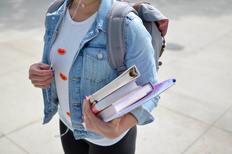 Symbolbild: Schülerin mit Rucksack und Büchern im Arm.