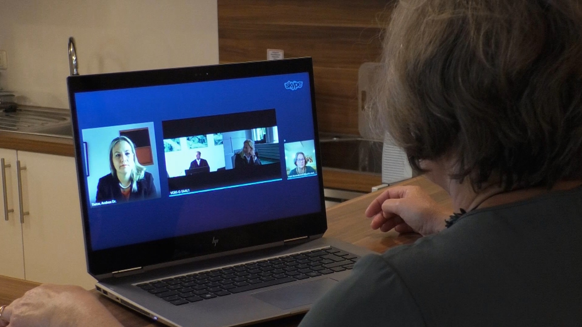 Frau sitzt vor Bildschirm ihres Laptops und nimmt an einer Videoverhandlung per Skype teil.